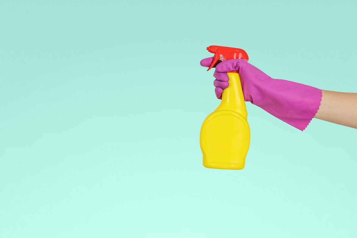 Unbranded household cleaning bottle held against a clear background